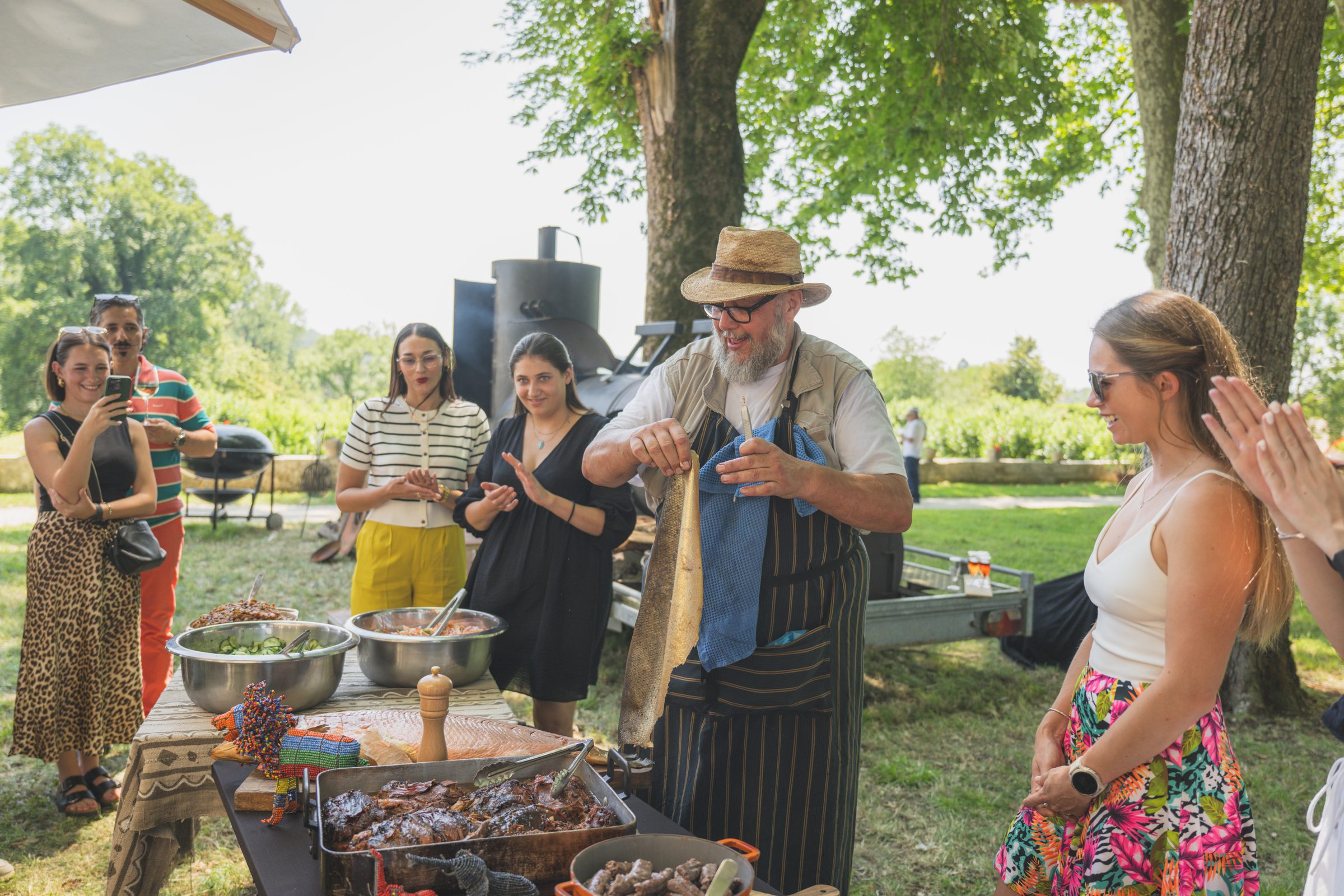 Kobus Botha soulevant un côté de poisson fumé du braai sous les applaudissements, les tables dressées sous les arbres