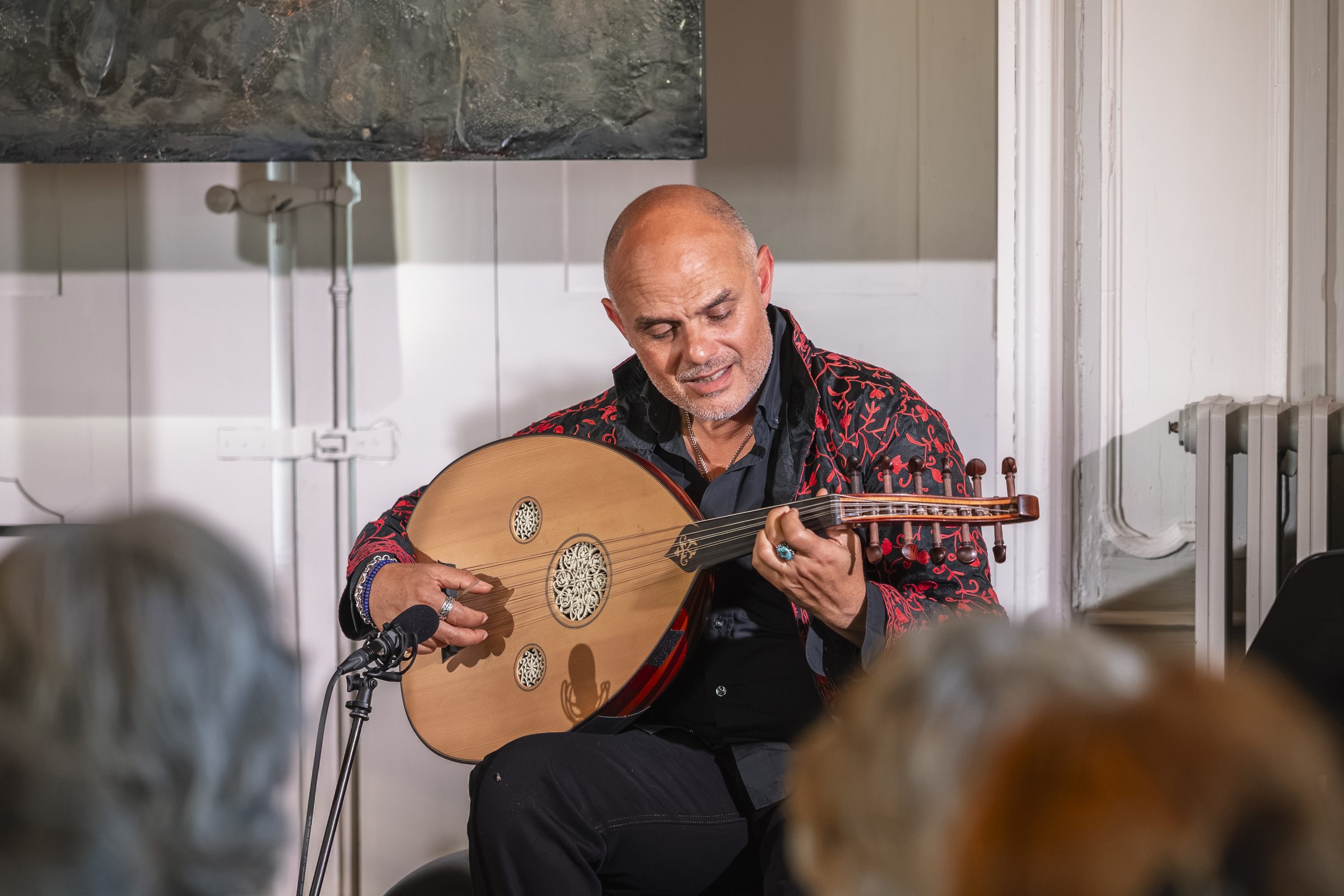 Ihab Radwan jouant de l’oud devant un public assis au salon