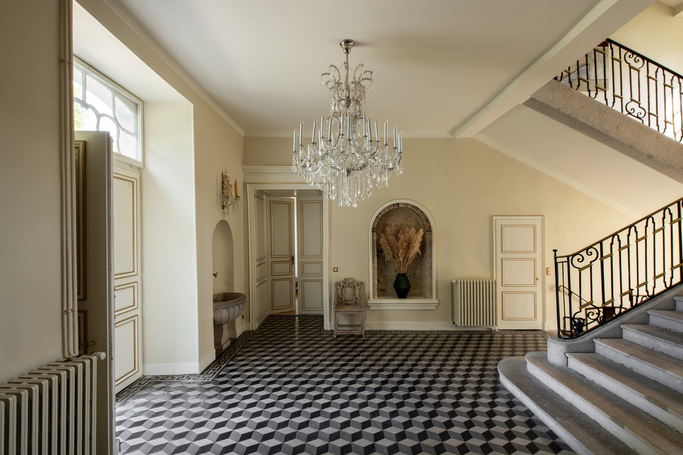 Le hall d’entrée du château, son damier de pierre sous le lustre de cristal