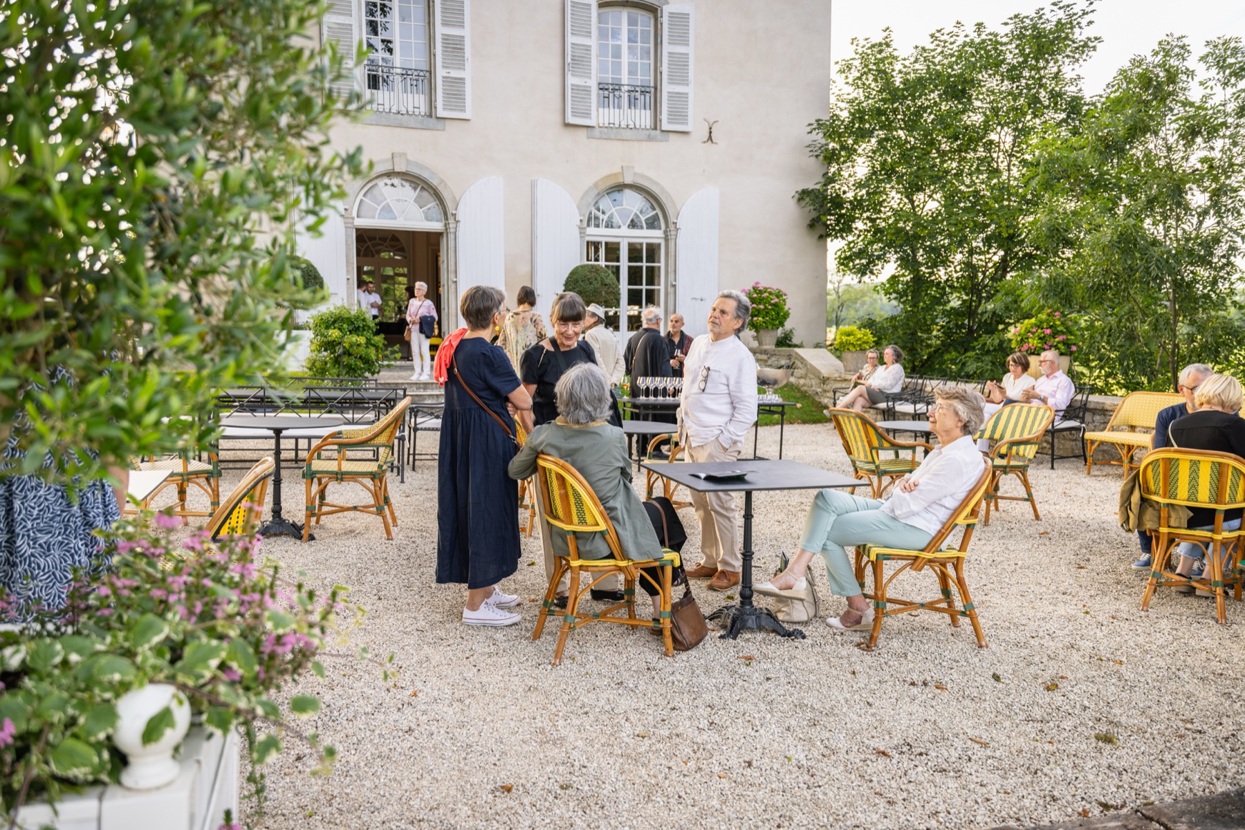 Des invités sur la terrasse un soir de Tétramorphe, devant la façade sud du château