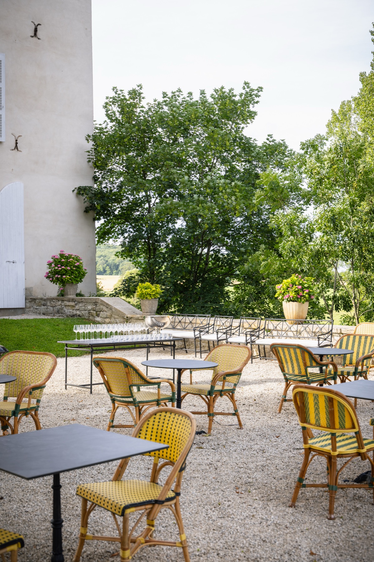 La terrasse dressée pour une réception, ses chaises de bistrot et ses flûtes alignées face à la vallée