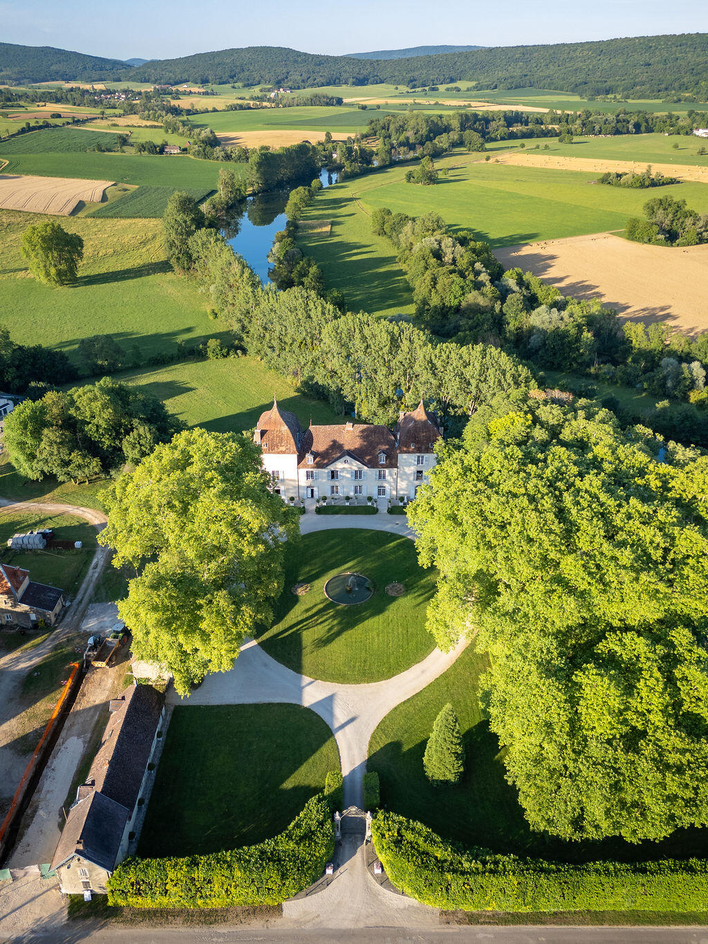 Vue aérienne du domaine, le château niché dans les arbres au bord de la Loue